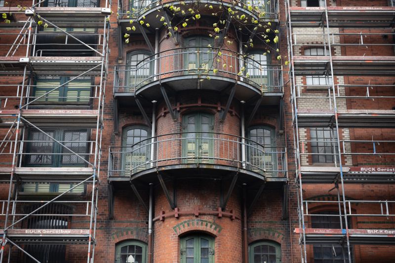 A brick apartment building under renovation, wrapped in scaffolding