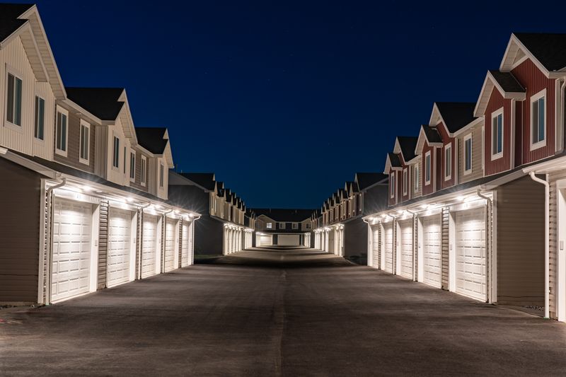 A row of modern townhomes on a residential street in the evening